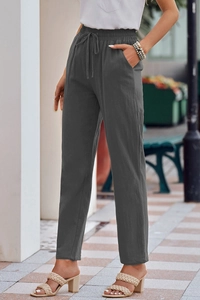 Detailed texture of dark grey linen trousers with drawstring waist and deep pockets