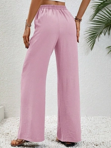 Dettaglio dei pantaloni rosa a vita alta e gamba larga con trama verticale ed elastico in vita