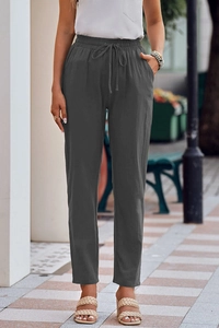 Detail of high-waist drawstring waistband and side pockets on dark gray linen pants