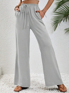 Dettaglio dei pantaloni grigi a gamba larga con vita alta, coulisse elastica e tasche laterali