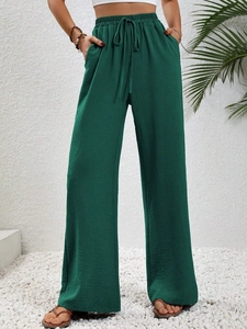 Dettaglio dei pantaloni a gamba larga verde scuro con coulisse elastica e tessuto a trama