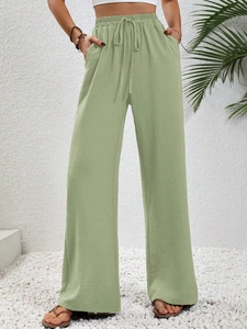 Dettaglio dei pantaloni a gamba larga verde salvia con elastico in vita e tasche laterali