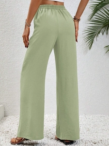 Dettaglio posteriore di pantaloni larghi verde salvia a vita alta con elastico in vita