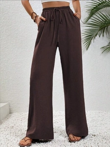 Dettaglio dei pantaloni a gamba larga marrone scuro con vita alta e coulisse regolabile