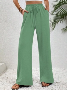 Dettaglio dei pantaloni a gamba larga verde salvia con coulisse e consistenza morbida