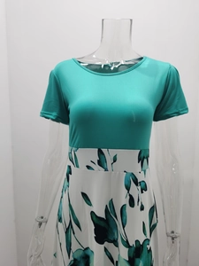 Détail du corsage bleu paon à col rond et de la jupe à fleurs à taille haute de la robe
