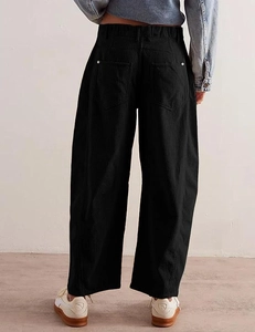 Detail of high-waist black corduroy trousers showing rear pockets and ribbed texture