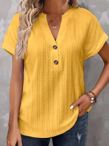 Dettaglio di t-shirt gialla brillante con scollo a V, tessuto operato e bottoni