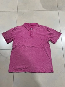 Detalle de polo de algodón lavado rosa con textura vintage y cuello de un botón
