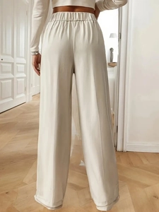 Detail view of high-waisted off-white trousers with premium drape and elegant texture