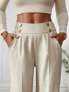 Close-up of high-waisted beige wide-leg trousers featuring four gold decorative buttons