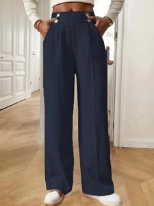Detail of high-waisted navy trousers with symmetric metal buttons and front pleats