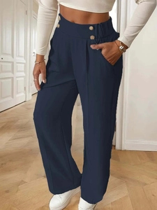 Detail of high-waist navy wide-leg trousers with gold buttons and vertical pleat