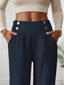 Detail of high waisted navy trousers with decorative gold buttons and side pockets