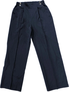 Detailed view of high waist trousers featuring decorative metal buttons and vertical pleats