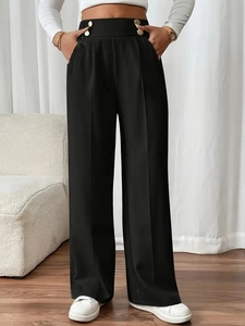 Detail of high-waist black trousers featuring gold decorative buttons and front pleats
