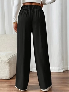 Rear view of high waisted black wide leg trousers showing draped fabric and elastic waist