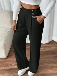 Detail of high waist black wide leg trousers showing metal button and elastic waistband