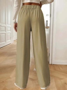 Detail of light khaki high-waisted wide-leg trousers with elastic waist and back crease