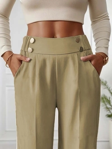 Detail of high waisted khaki trousers with bronze button accents and pleated texture