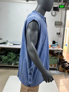 Dettaglio di una camicia senza maniche in denim blu con cuciture a contrasto su un manichino