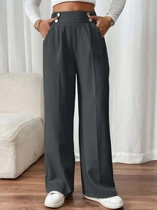 Detail of high waist trousers showing gold buttons on dark grey fabric texture