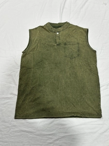 Dettaglio di una maglia henley senza maniche verde oliva con taschino e trama lavata