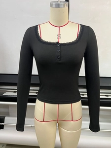 Détail du haut en maille côtelée noire avec dentelle au décolleté en V et boutons décoratifs