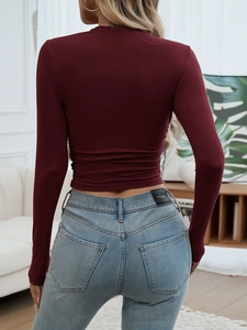 Detail view of wine red slim fit long sleeve top featuring side ruched elastic texture