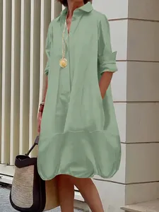 Detail of mint green button-down shirt dress with long sleeves and loose fit silhouette