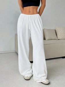 Detailed view of elastic high waistband with drawstring on white wide leg sweatpants