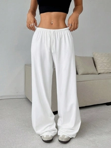 Detail of white wide-leg sweatpants showing drawstring waist and knit fabric texture