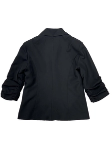 Dettaglio posteriore di un blazer nero slim fit con eleganti maniche a tre quarti arricciate