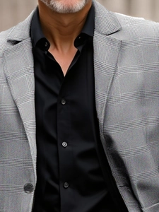 Detail of grey Glen Check blazer lapel paired with a black business shirt for men