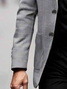 Detail of grey plaid blazer sleeve buttons and structured polyester fabric texture