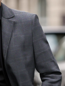 Detailed close-up showing the grey plaid fabric texture and pattern of the blazer jacket
