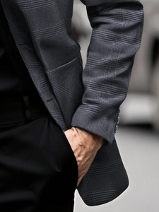 Close-up of grey plaid suit jacket cuff with decorative buttons and fine fabric texture
