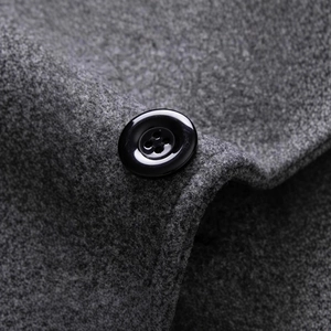 Close-up of grey wool blend overcoat fabric featuring a glossy black resin button detail