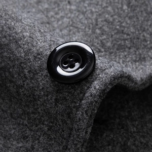 Men's wool coat detail showing a black polished button and gray fabric texture