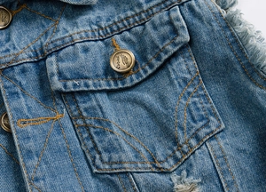 Close-up of light blue slim fit denim vest with vintage metal button and frayed edges