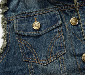 Detail of blue denim vest showing washed fabric, orange stitching and vintage metal button