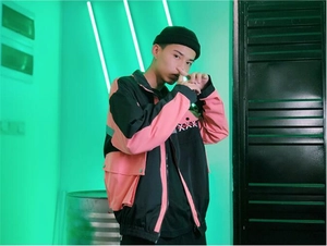 Close-up of pink and black color-block techwear jacket with cross embroidery detail