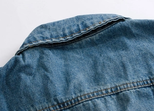 Detail of blue denim vest showing the collar, shoulder seams and yellow contrast stitching