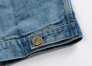 Detailed macro view of the washed blue denim vest hem with a branded bronze metal button