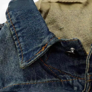 Close-up of slim fit denim vest with orange double stitching and metal button details