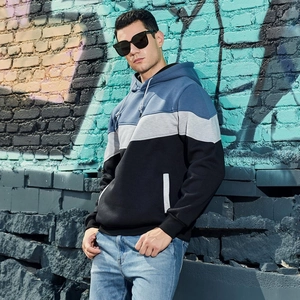 Detail of color-block hooded sweatshirt featuring blue, grey, and black panels