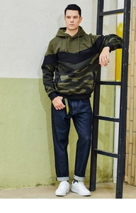 Detail of color-block camouflage hoodie with khaki shoulders and dark raw denim jeans