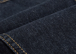 Gros plan sur la texture denim bleu foncé avec coutures jaunes contrastées
