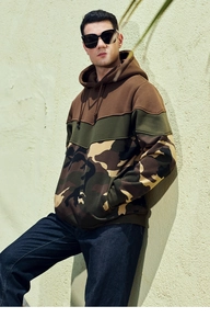 Detail of color block camo hoodie featuring brown and green patchwork with drawstring hood
