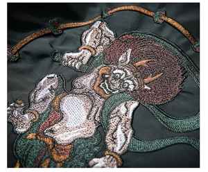 Detailed macro view of the intricate Japanese Raijin embroidery on black satin jacket fabric